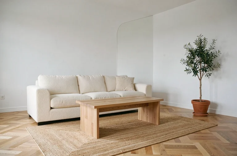 Salon minimaliste scandinave avec canapé en bouclé crème, table basse en chêne et parquet à chevrons pour tendances déco 2024